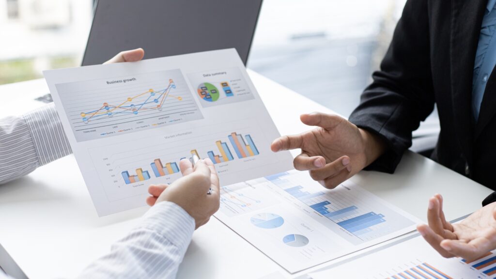 Two business people holding charts and discussing them