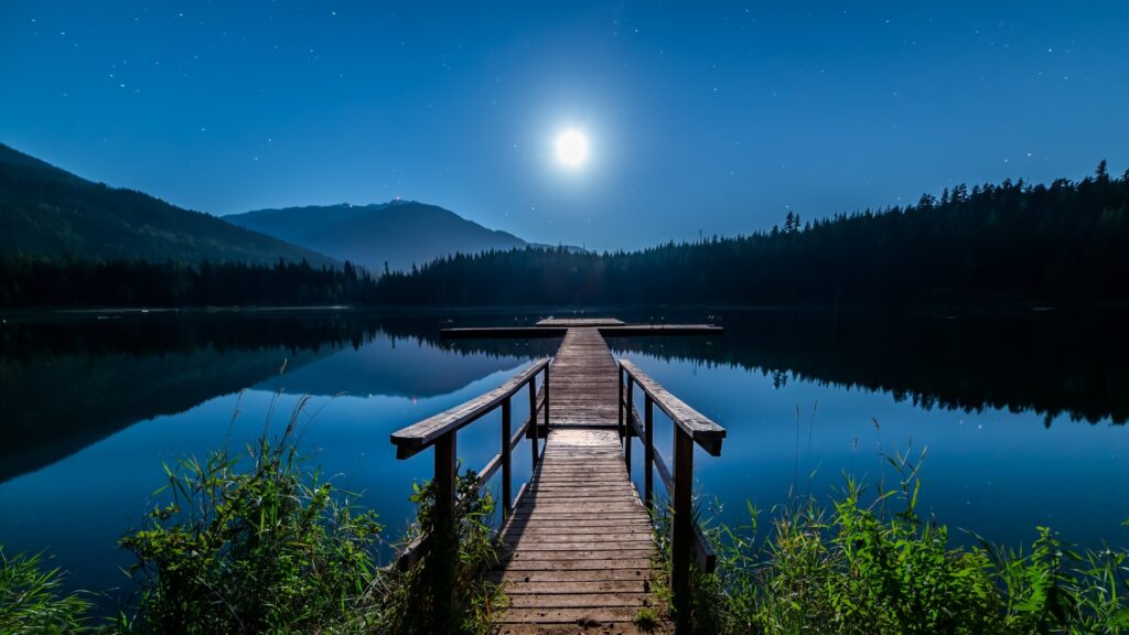 Pier extending into a lake under a full moon