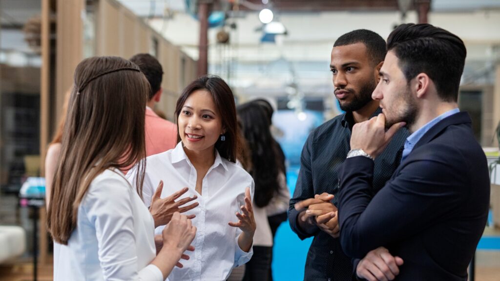 Four people stand in a circle listening and talking to each other