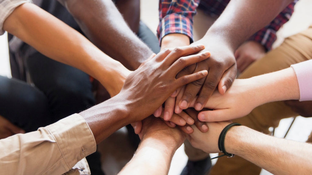 A group in a circle stack their hands on top of each other