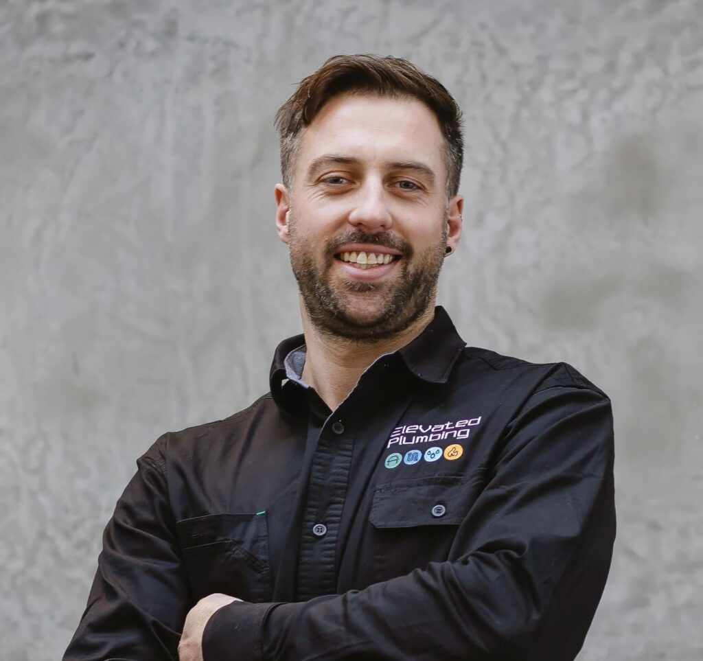 man stands in his uniform with arms crossed, smiling